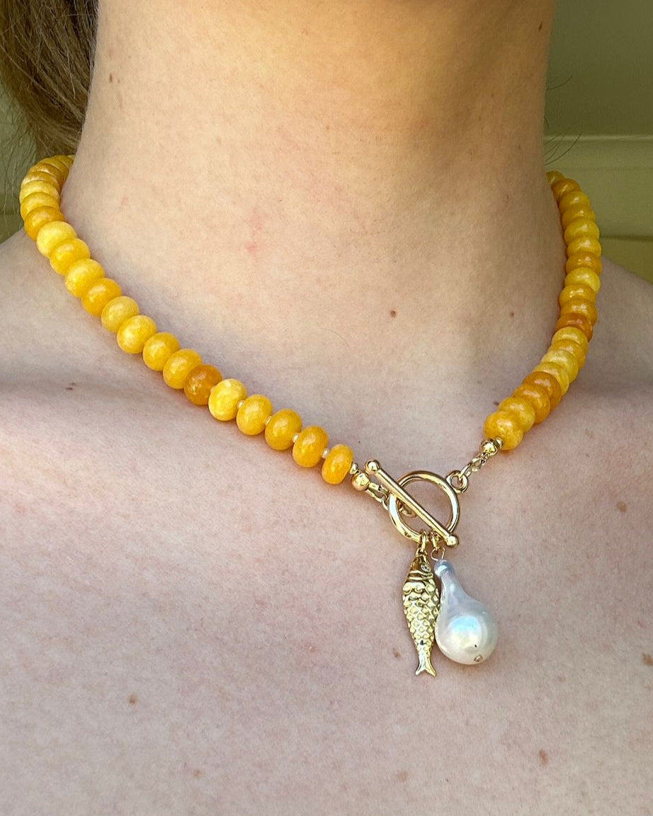 Yellow beaded necklace with a pendant on a person's neck