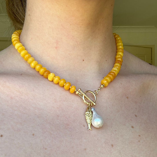Yellow beaded necklace with a pendant on a person's neck